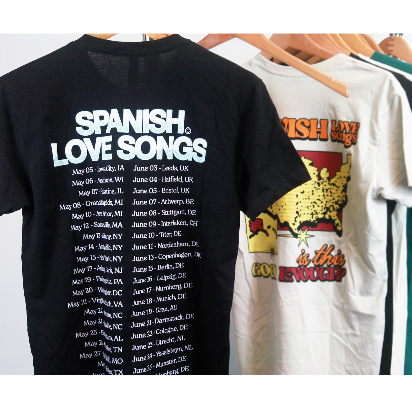 image of the back of a black tee shirt hanging. the back of the tee full print that says at the top spanish love songs and a list of the 2022 spring tour dates and locations below