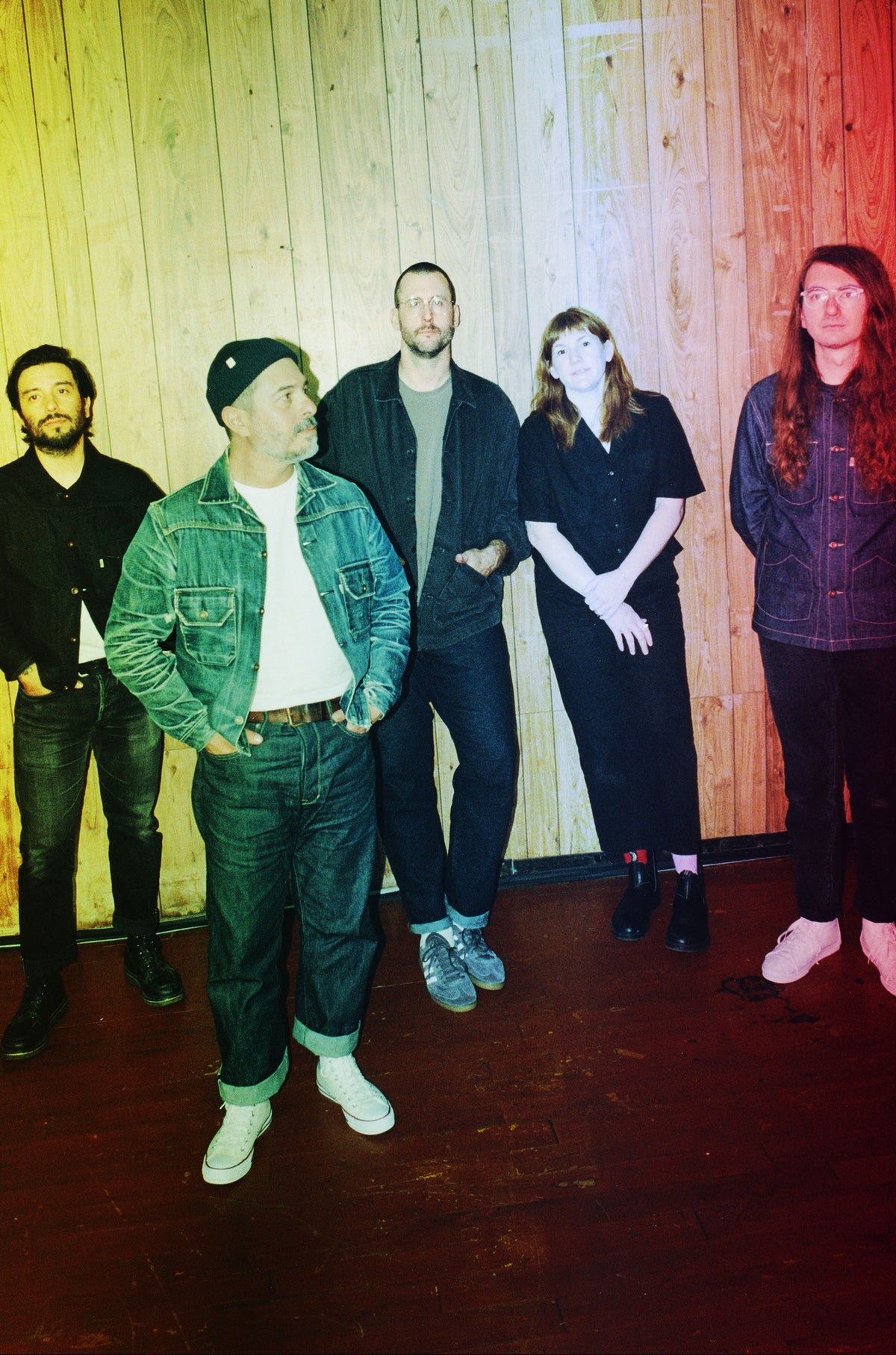 Five people standing together in front of a wood-paneled wall, with a strong yellow, green, and red color cast over the photo.